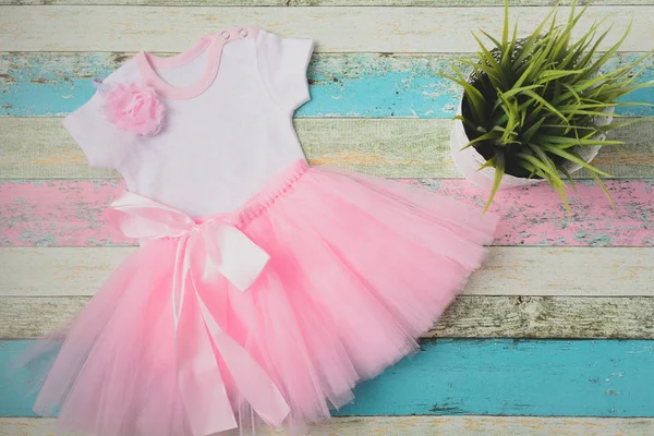 Ensemble bébé - jupe en tulle rose, body blanc des cœurs et un beau bandeau rose sur fond bois pastel. Vue de dessus, plan plat . — Photo