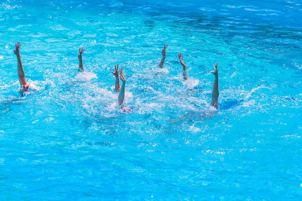 Natação sincronizada. Pernas femininas magras bonitas na água de uma piscina. Conceito de beleza, arte, atletismo e sincronicidade . — Fotografia de Stock