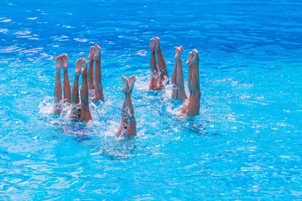 Synkroniserad simning. Vackra lean kvinnliga ben i vattnet i en pool. Begreppet skönhet, artisteri, atletiska och synkronicitet. — Stockfoto