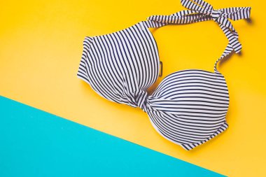 Üstten görünüm çizgili mavi ve beyaz mavi ve sarı pastel arka plan üzerinde sutyen yüzme. Uzay kopyalayın. Tatil kavramı