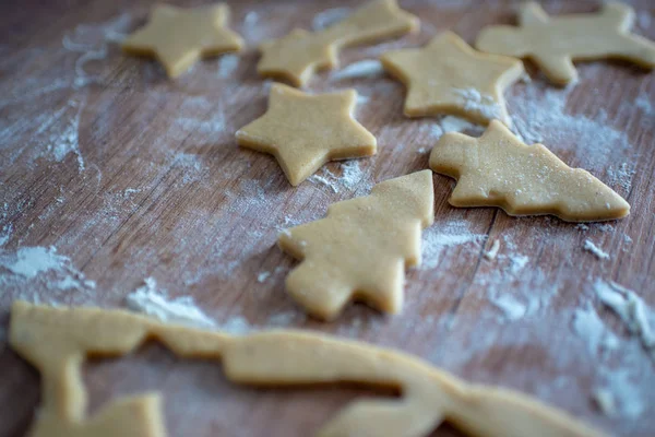 Christmas cookies preparation. Cookies cutter, dough for cookies and rolling pin on the kitchen table. Homemade treats. Selective focus.