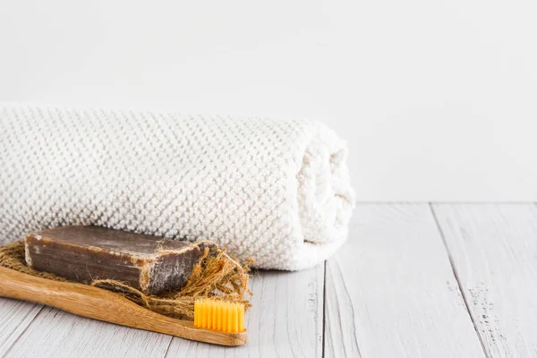 Бар натурального органического мыла ручной работы, зубная щетка бамбука и белое полотенце на белом фоне, пустое место для текста . — стоковое фото