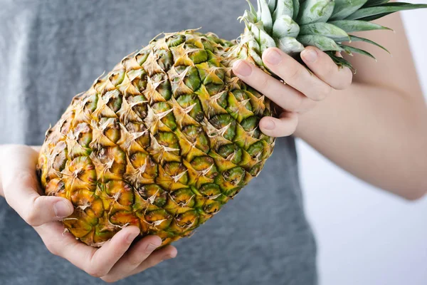 Meisje houdt een ananas in handen op witte achtergrond. Tropische, vacantion en zomerse Vibes. Minimalistische photoshot. — Stockfoto