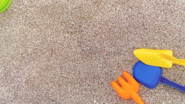Jouets pour enfants en plastique dans le sable. Concept de vacances en famille. Vue de dessus. Espace pour le texte . — Photo