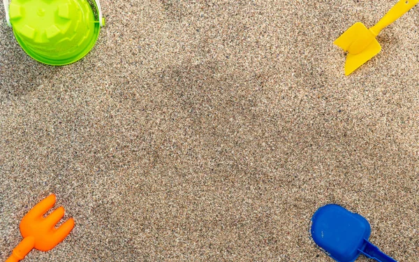 Jouets pour enfants en plastique dans le sable. Concept de vacances en famille. Vue de dessus. Espace pour le texte . — Photo