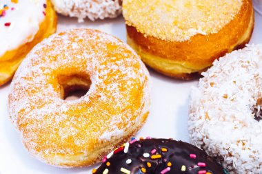 Çikolata kaplı, jöleli ve üzerine donut serpiştirilmiş bir fırın kutusunda çok renkli çörekler. Şeker bağımlılığı ya da festival menüsü konsepti.