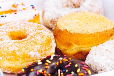 Çikolata kaplı, jöleli ve üzerine donut serpiştirilmiş bir fırın kutusunda çok renkli çörekler. Şeker bağımlılığı ya da festival menüsü konsepti.