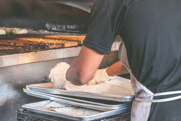 アメリカ、ニューヨーク:伝統的なベーグル・ベーカリー。ベーカーは、オーブンで焼くためのゴマと本格的なニューヨークスタイルのバゲルを準備する過程で. ロイヤリティフリーのストック画像