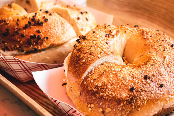 Freshly baked, crunchy typical NYC bagels with sesame, poppyseed topping, cream cheese spread and lox from coffee shop, cafe or bakery in Manhattan, New York City, close up with selective focus.