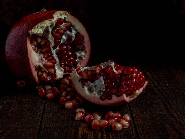 Fresh pomegranate with grains on black background. — Stock Photo, Image