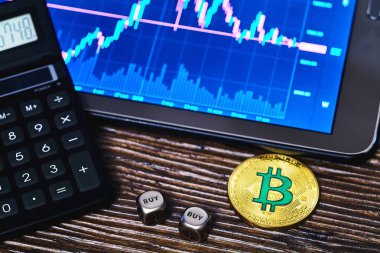 Bir hesap makinesi, tablet ve dices bir masada altın bitcoin