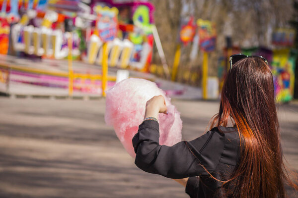 Young woman standing with pink cotton candy p in amusement Park