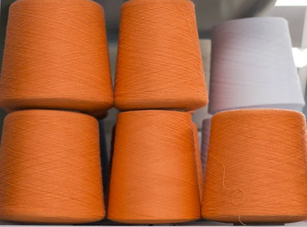 orange yarn in coils on the shelf in production