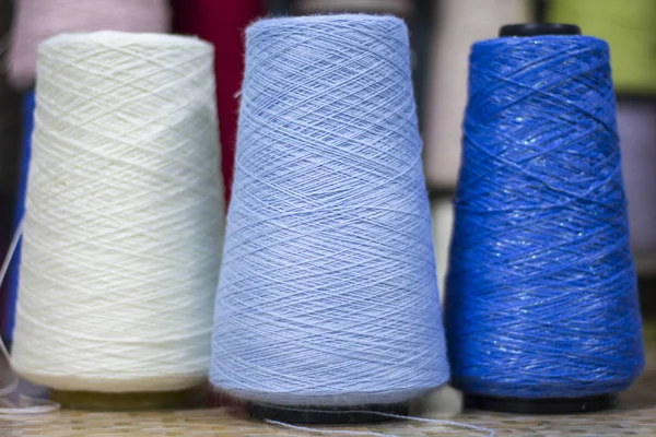 three reels of two blue shades of yarn and one white