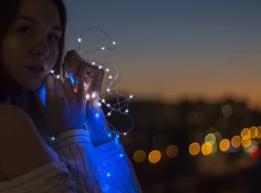 pencerenin yanında onun elinde parlayan çelenk ile kız