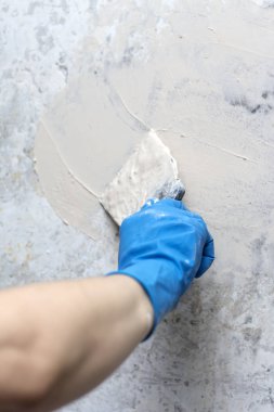 duvarlar, macun bir spatula ile smear mavi eldiven kadında tamiri