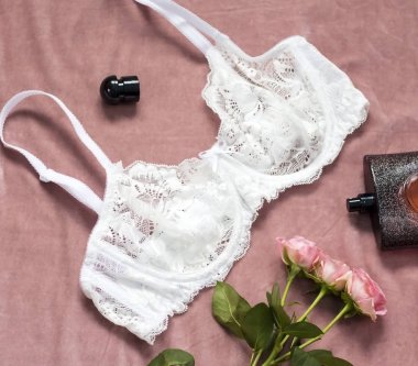 gül çiçek ve parfüm şişesi ile beyaz arka plan üzerinde beyaz dantel sütyen