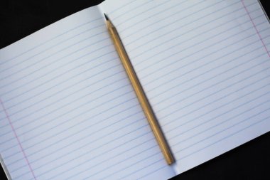 Not defteri ve siyah bir arka plan üzerinde basit bir kalem.