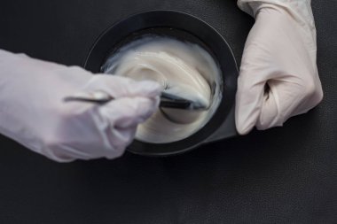 Kuaför ve saç boyası siyah bir zemin üzerine karışımları kase tutar