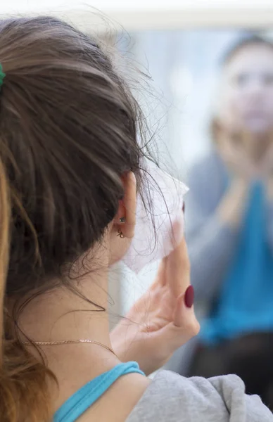 the girl makes a cloth mask in front of the mirror