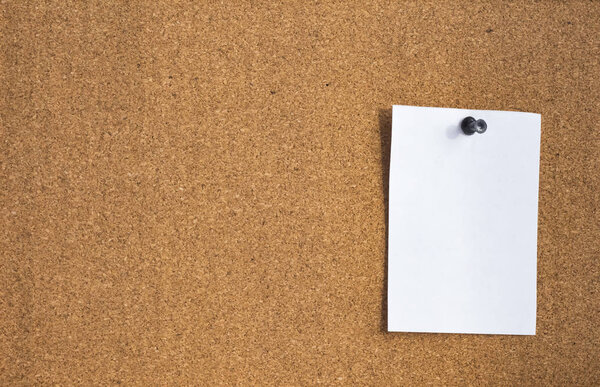 a blank sheet of paper attached to a cork Board by a push-button stationery