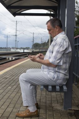 Tren platfo bekleyen hipster işadamı ile smartphone,