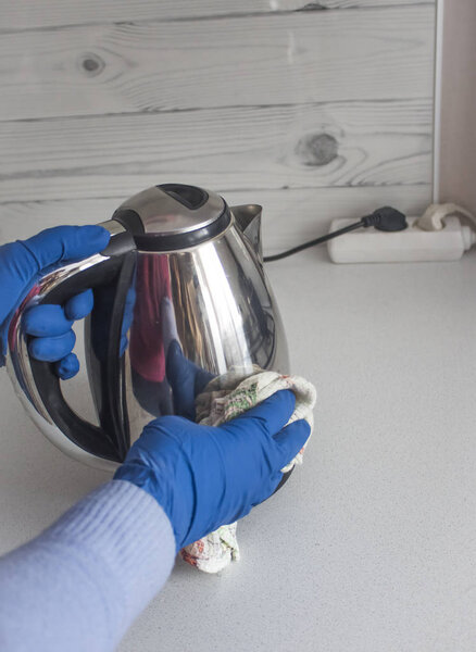 Женщина вытирает чайник из грязи тряпкой
