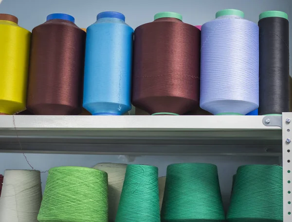 elastic and cotton threads on spools on the shelf in production