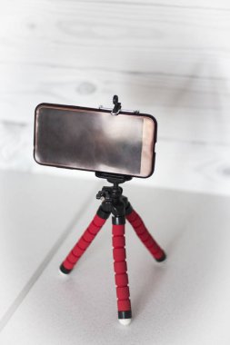 Beyaz zemin üzerine kırmızı tripod üzerinde Smartphone