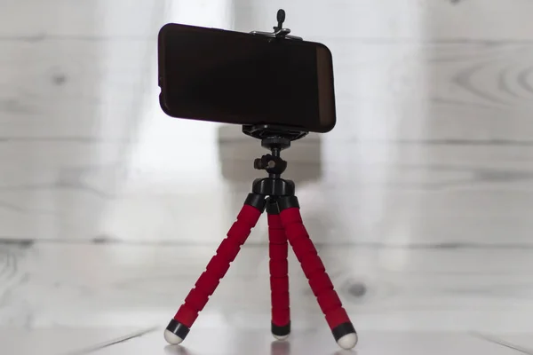 Smartphone on a red tripod on a white kitchen background — Stock Photo, Image