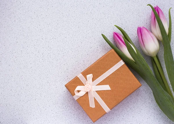 Three delicate pink tulips on white background with gift box and copy space Royalty Free Stock Photos