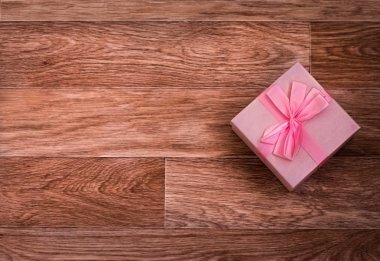 Tahta arka planda fiyonklu hediye kutusu