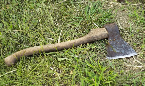 Scherpe oude bijl liggend op het groene gras — Stockfoto