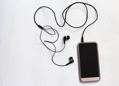 Boş ekrana sahip akıllı telefon, beyaz arka plan üst görünümünde spiral kabloile kulaklıklara bağlanır