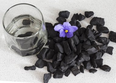 Shungite stones in a glass of water to clean and recharge water ,close-up view from above clipart