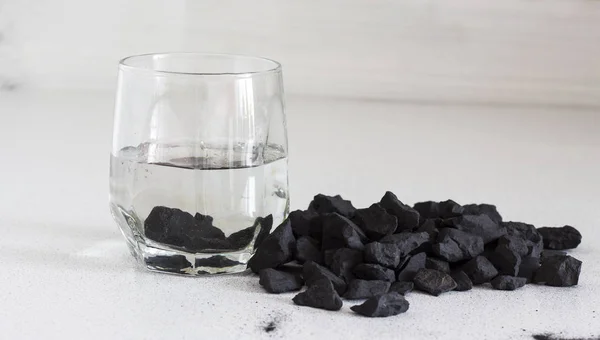 Yüksek karbon içeriği ve metafizik özellikleri nedeniyle su arıtma ve şarj için alternatif tıpta kullanılan beyaz bir arka plan üzerinde Rus shungite taşlar