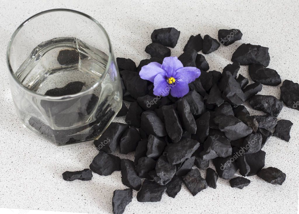 Shungite stones in a glass of water to clean and recharge water ,close-up view from above