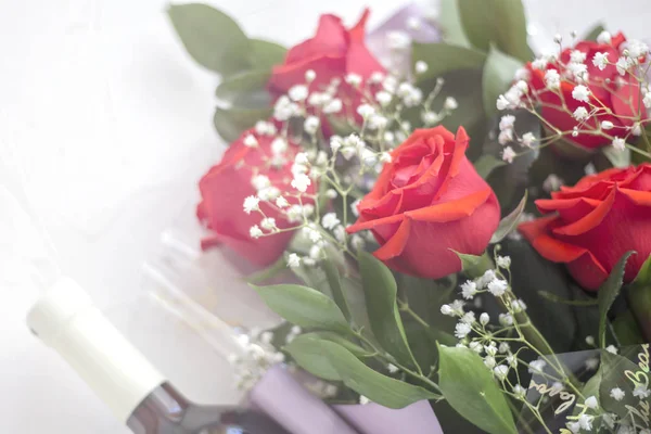 Bouquet of red roses with a bottle of wine on a white background in white blurred light — Stock Photo, Image