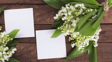 metin için beyaz bir kağıt levha ile kahverengi ahşap bir arka plan üzerinde vadinin narin beyaz zambak düz yatıyordu buket