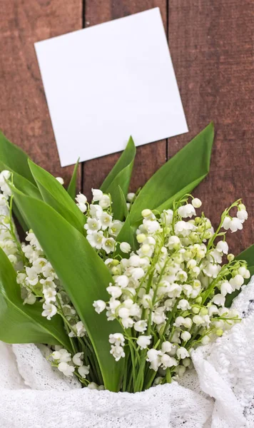 Boeket van witte lelies van de vallei op een bruine houten achtergrond en een kopie van de ruimte — Stockfoto