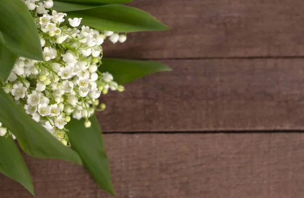 Boeket van witte lelies van de vallei op een bruine houten achtergrond en een kopie van de ruimte — Stockfoto