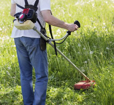 adam bir benzin düzeltici ile çim çimlerini biçiyor