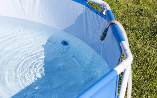 Sommarträdgård pool fylld med vatten från en slang — Stockfoto