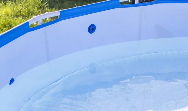 Ett fragment av poolen fylld med rent vatten från en slang i trädgården — Stockfoto