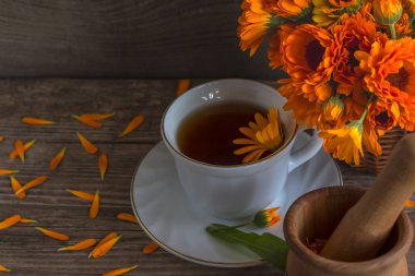 Otlar taşlama için havaneli ile ahşap bir arka plan ve harç üzerinde calendula ile Çay