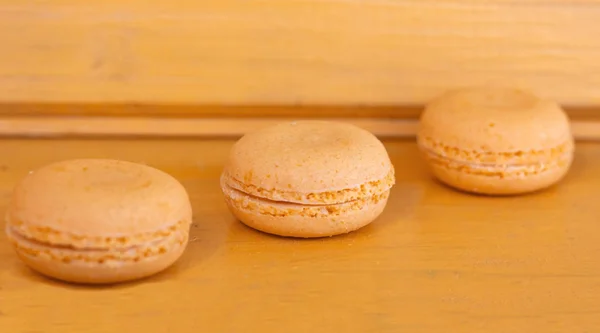 Three delicate yellow macaroons almond cakes on a yellow background — Stock Photo, Image