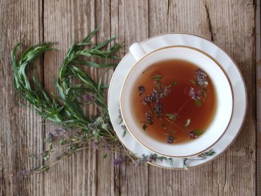 mekanın bir kopyası ile ahşap bir arka plan üzerinde kekik ve tarhun ile sıcak kokulu çay bir Fincan