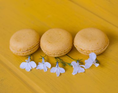 beyaz çiçekler ile sarı arka plan üzerinde sarı macaroons kek