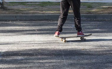 Güneşli havalarda asfalt üzerinde bir çocuk kaykaylar