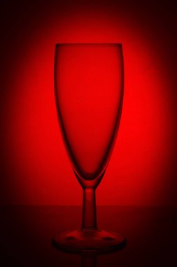 bir vinyet ile kırmızı bir arka plan üzerinde lümen üzerinde boş cam şampanya cam